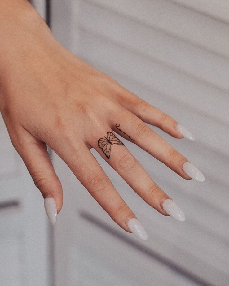 9. Tatuaggio di un dito a farfalla con la parola "amore".