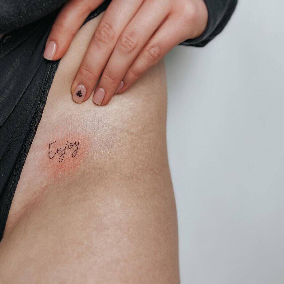 A tattoo of “enjoy” on the hip