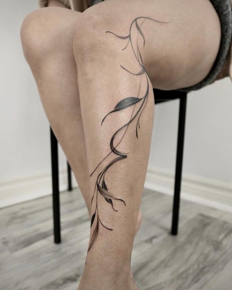 A brushstroke shin tattoo of leaves and vines