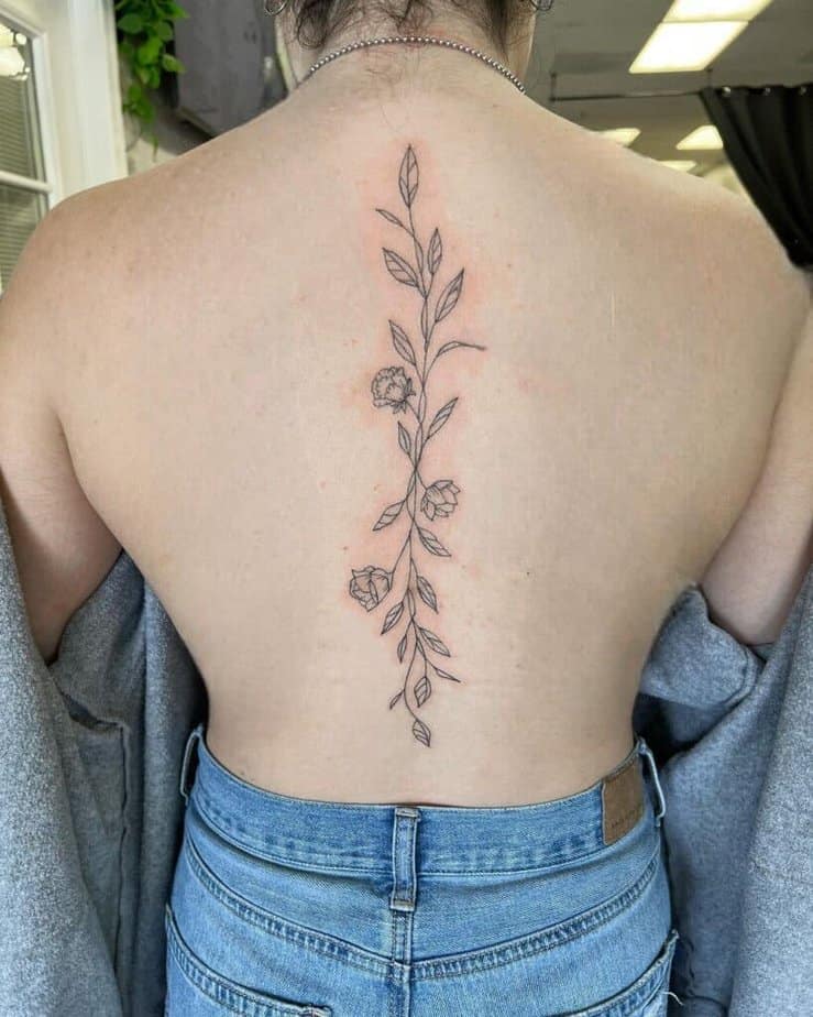 A cute spine tattoo with flowers and leaves