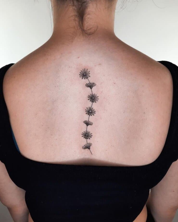 Un tatuaggio a forma di margherita sulla spina dorsale
