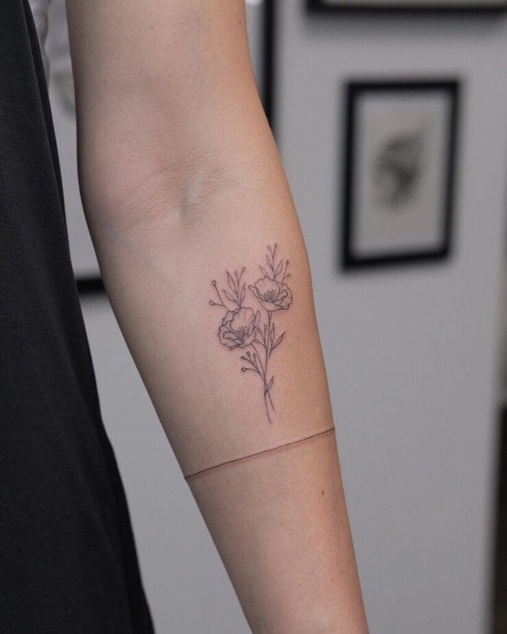 A fine-line tattoo of a bouquet of poppy flowers