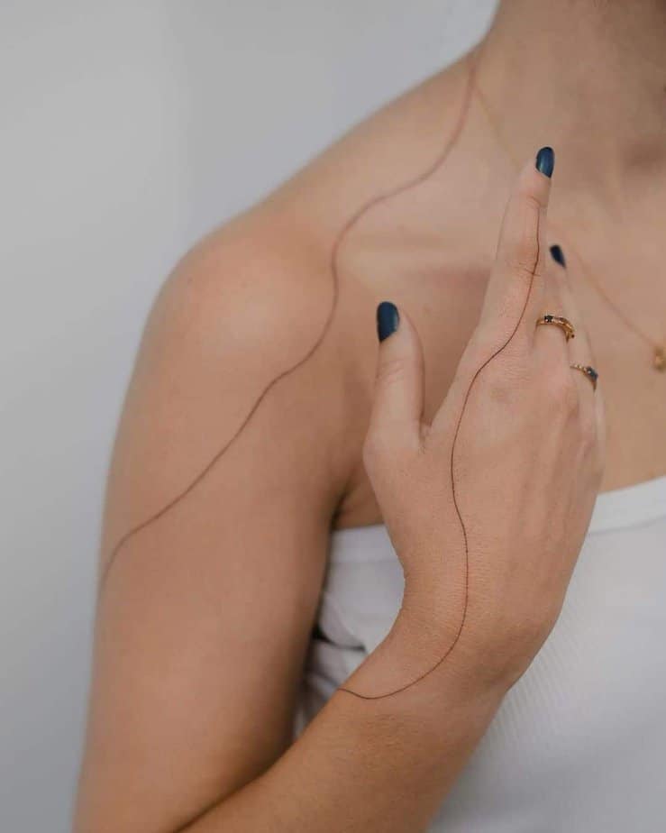 Un tatuaggio a forma di linea che si estende dal dito al resto del corpo.