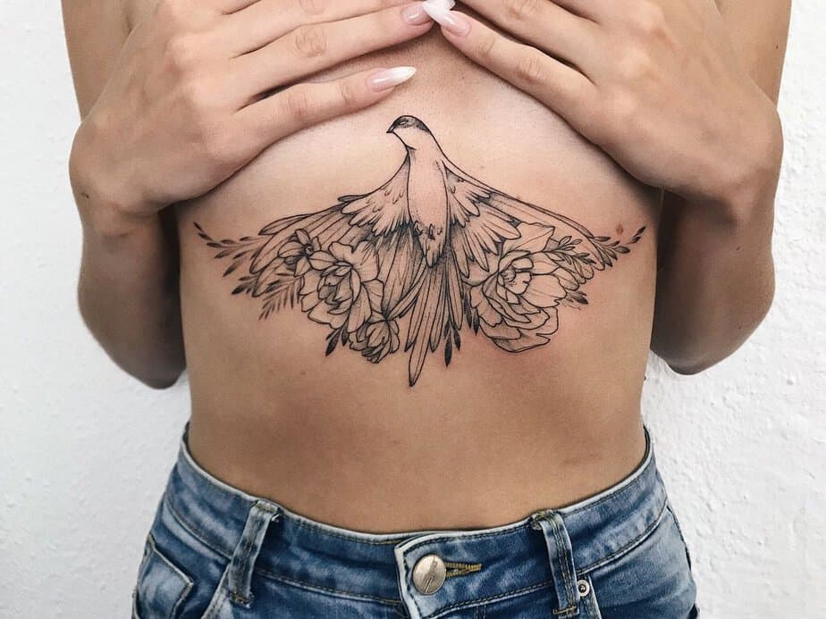 A middle chest tattoo of a bird with flowers
