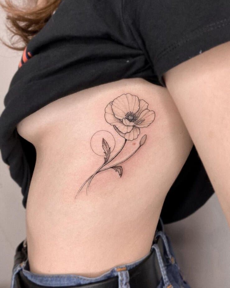 A poppy flower tattoo on the ribcage