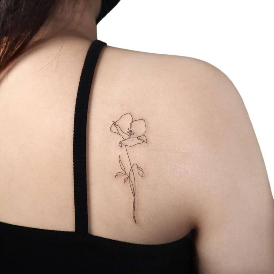 A simple, sleek poppy flower tattoo on the shoulder