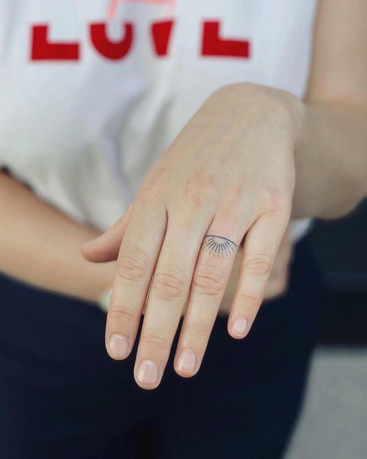 A sun tattoo on the ring finger