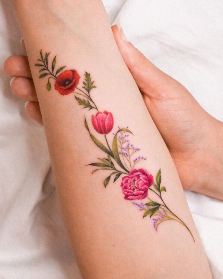 A tattoo of a vine of flowers on the forearm