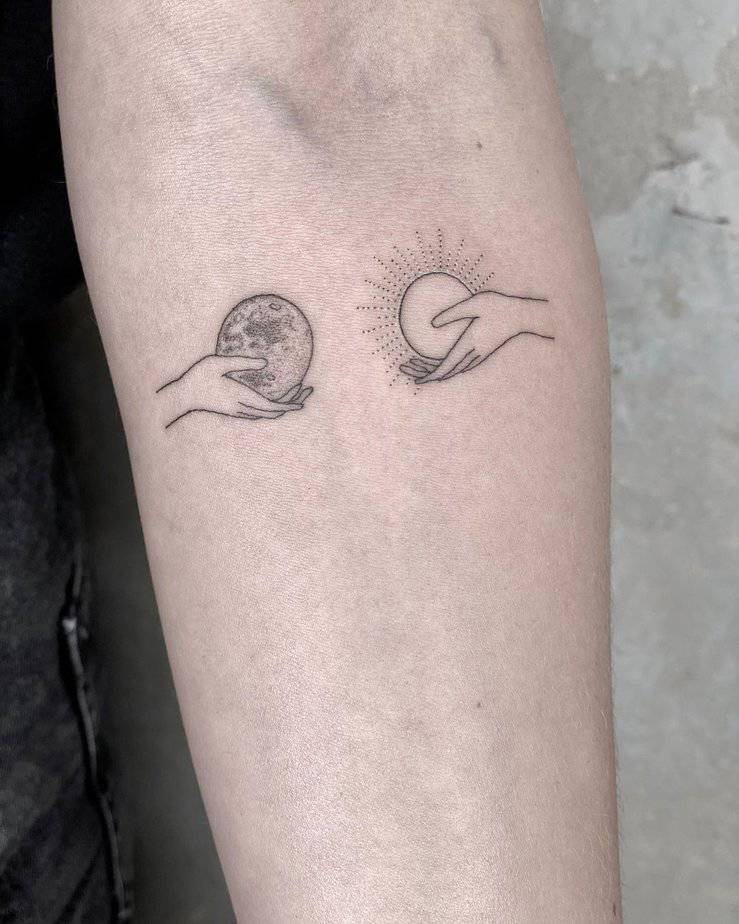 A tattoo of two hands holding the sun and the moon