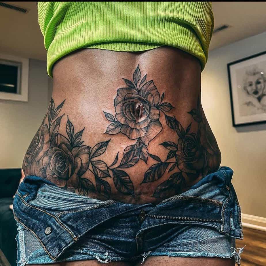 12. A tummy tuck tattoo with black roses
