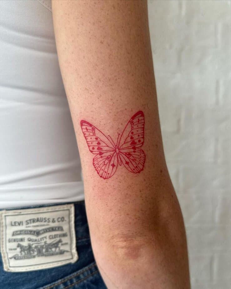 18. A fine-line red butterfly tattoo