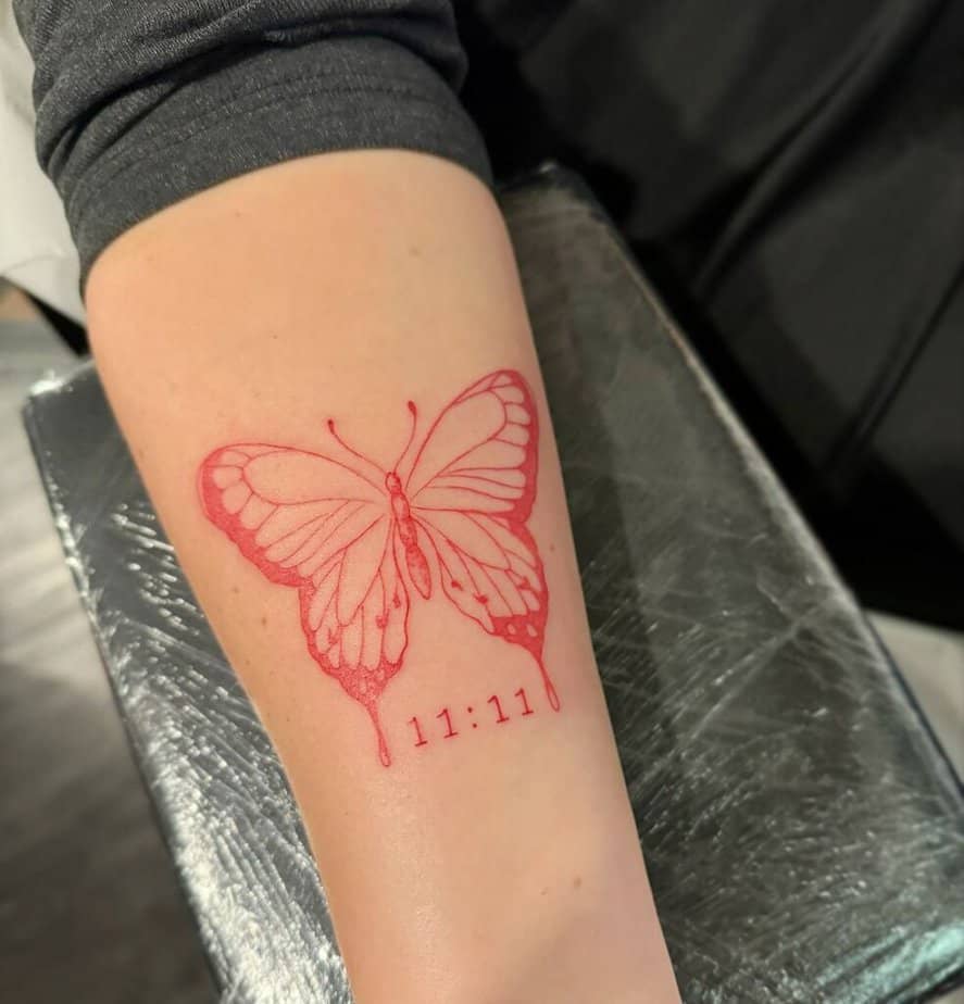 22. Un tatuaggio a forma di farfalla rossa con 11:11 