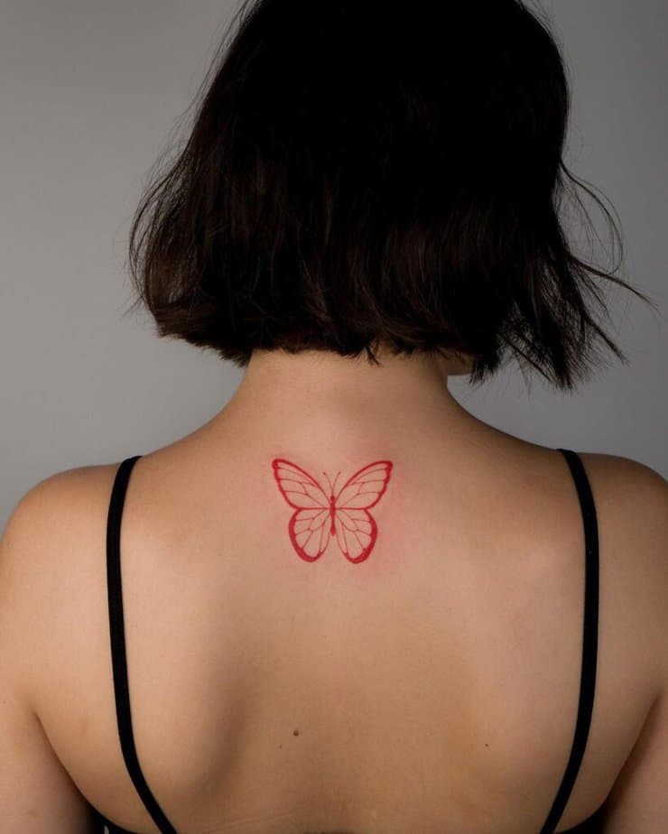25. A fine-line red butterfly tattoo on the back