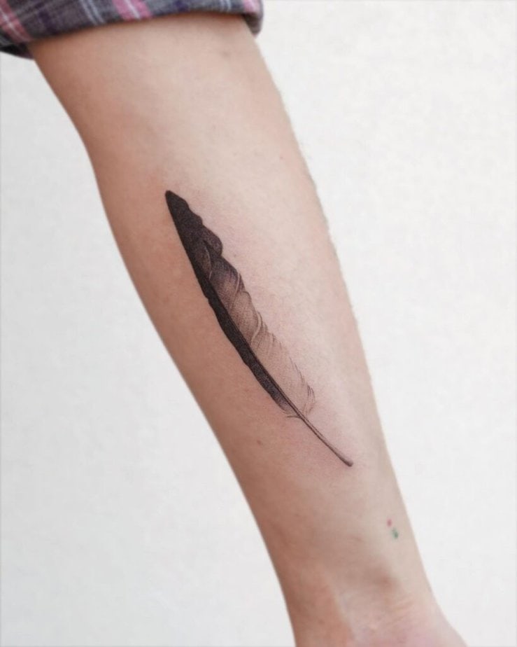 2. Un tatuaggio con una lunga piuma sull'avambraccio 