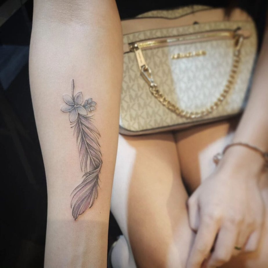 20. A tattoo of a feather with a flower 