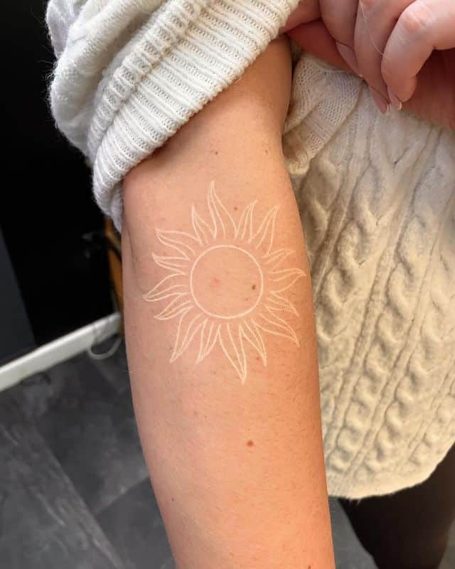 White tattoo of a Sun