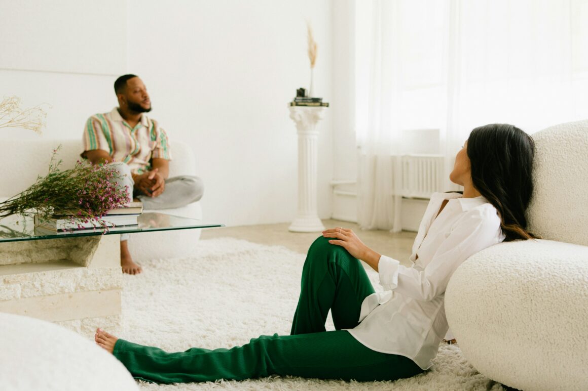 A woman sitting on the floor in front of a man.