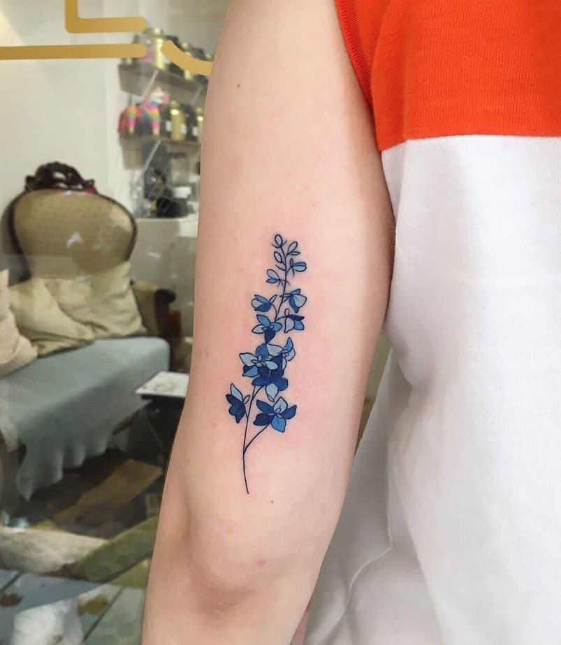 14. Bright blue larkspur tattoo on the arm