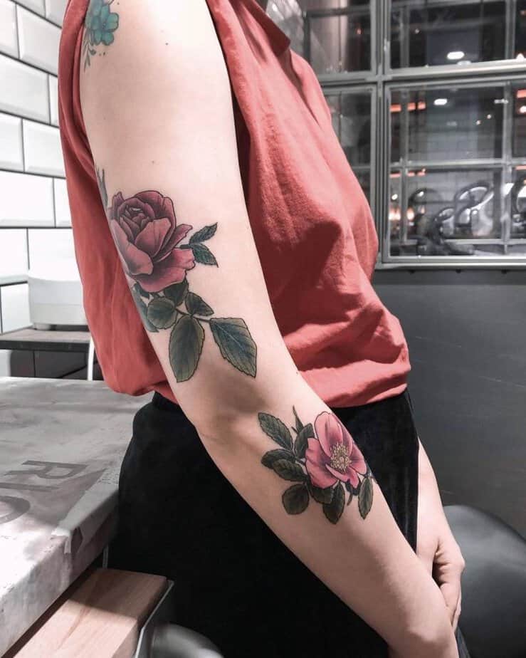 16. A large pink rose tattoo on the arm with leaves