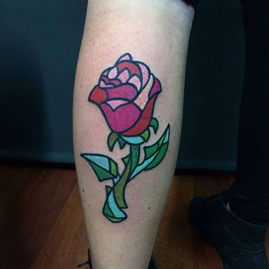 20. A stained glass style pink rose tattoo on the calf