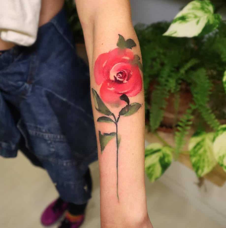 4. A watercolor pink rose tattoo on the forearm