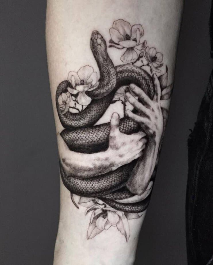 6. Black mamba with hands and flowers tattoo