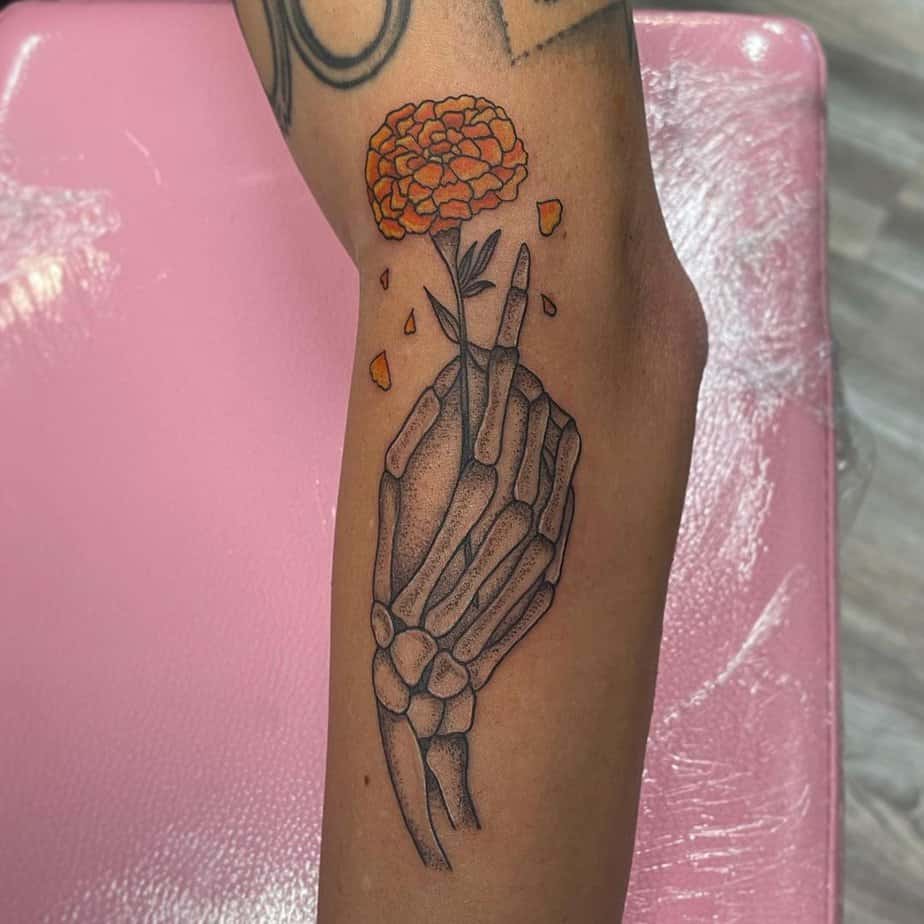 Skeleton hand with a marigold flower